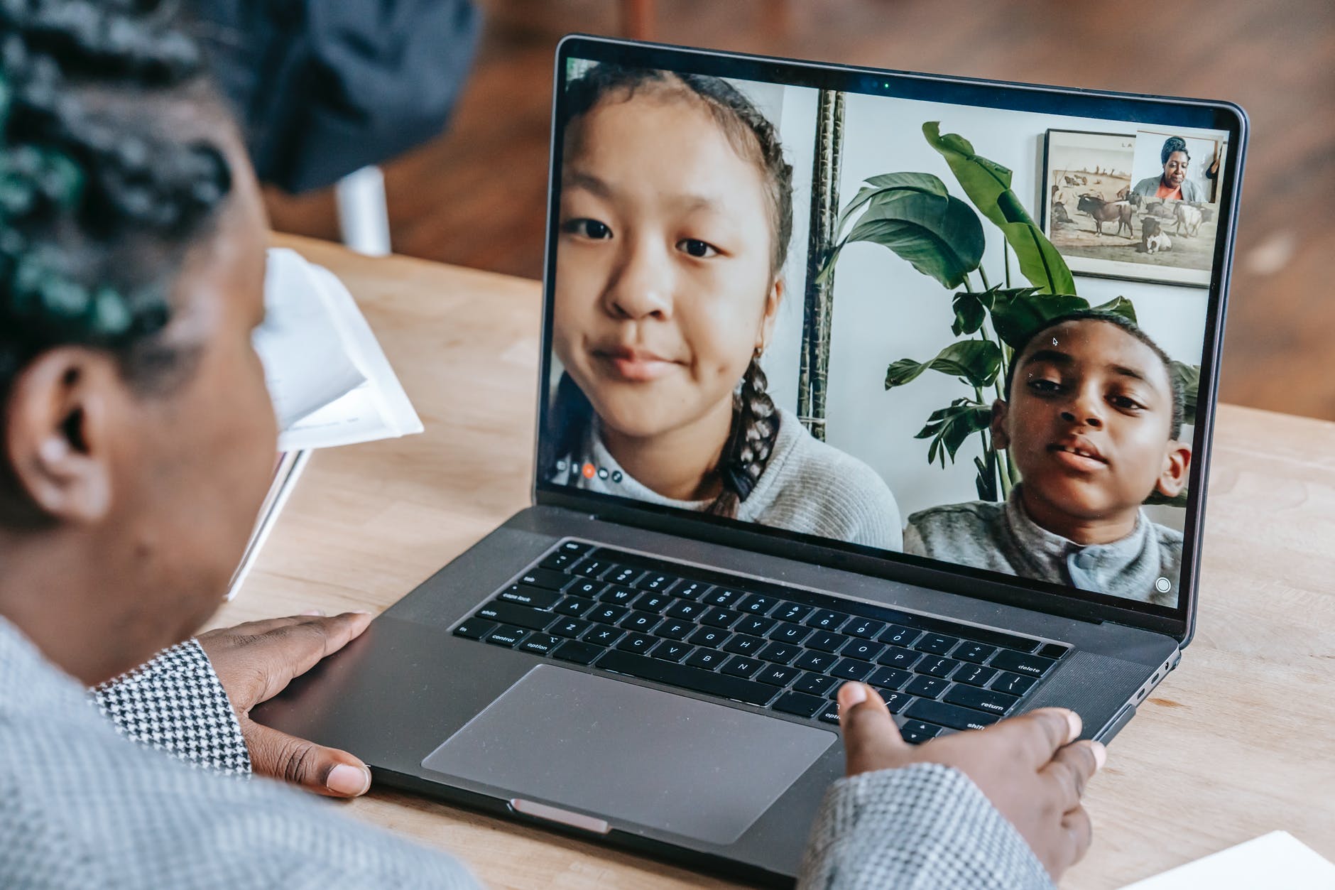 black woman working online with pupils on laptop